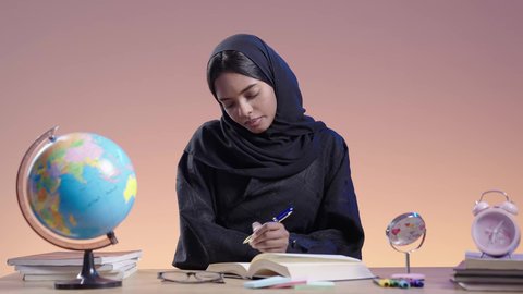 التزود بالعلم والمعرفة، قضاء وقت الفراغ بالتثقيف والتعلم، مفهوم محو الأمية، طالبة جامعية سمراء عربيه سعوديه ترتدي العباءه والحجاب تمارس هواية مطالعة الكتب المفيدة في وقت الفراغ، القراءه بإيماءات التمعن والتركيز