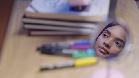 مفهوم الدراسة والتعلم ، مدارس وجامعات المملكه العربيه السعوديه، تصوير مقرب لوجه طالبه جامعيه عربيه سعوديه خليجيه سمراء تتحدث  وتتكلم عن شيء ما ، ملامح  وجه حاده ، خلفيه ضبابيه لمجموعة كتب واقلام حبر ملونه