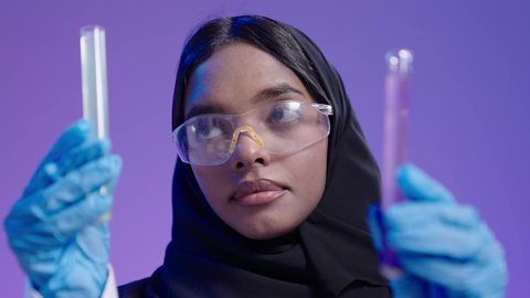 استخدام الانابيب في اجراء التجارب العلمية داخل المختبر الكيميائي الجامعي، التعليم في المملكة العربية السعودية، مفهوم البحوث العلمية، طالبة جامعية سمراء عربيه سعوديه ترتدي العباءه والحجاب