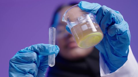 مفهوم البحوث العلمية، التعليم في المملكة العربية السعودية، طالبة جامعية سمراء عربيه سعوديه ترتدي العباءه والحجاب، استخدام الانابيب في اجراء التجارب العلمية داخل المختبر الكيميائي الجامعي