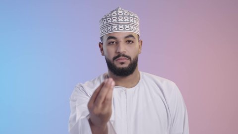 الهدوء وطلب التوقف، بورتريه لرجل عربي خليجي عماني يرتدي الدشداشه والكمه وينظر الى الكاميرا ، الاشارة بإيماءات الصبر والتأن والتريث، إمهال الوقت والإنتظار للقيام بشيء ما، خلفية ملونه