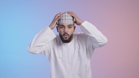 الخسارة والفشل في تحقيق الأهداف, الشعور بالانزعاج والصدمة, تعابير الاندهاش بسماع الاخبار السيئة, شاب عربي خليجي عماني يرتدي الدشداشه والكمه يضع يديه على رأسه بإيماءات الذهول، خلفية ملونة
