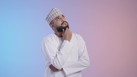 التأمل والتخطيط للمستقبل، تعابير شرود الذهن والتمعن، ايجاد حل لمشكلة ما، رجل عربي خليجي عماني يرتدي الدشداشة والكمة يضع يده على رأسه بايماءات التفكير والتركيز، المشاكل والهموم والضغوطات المحيطة، خلفية ملونه