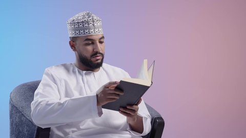 قضاء وقت الفراغ بالتثقيف والتعلم،  التزود بالعلم والمعرفة ،مفهوم محو الأمية، رجل عربي خليجي عماني يرتدي الدشداشه والكمه يمارس هواية مطالعة الكتب المفيدة في وقت الفراغ، القراءه بإيماءات التمعن والتركيز