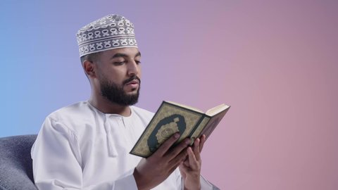 الشعور بالخشوع والطمأنينة، تلاوة وقراءة القرآن الكريم وتدبر معانيه، رجل عربي خليجي عماني يرتدي الدشداشة والكمة يحمل بيده المصحف الشريف، الإكثار من ذكر الله تعالى، خلفية ملونه