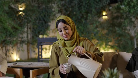 تجسيد مفهوم حسن الضيافة والكرم العربي،دلة القهوة العربية تراث قديم، التنزه والتسلية في شاليه سياحية في وقت العطلة ،اجتماع الأهل والأصدقاء في الهواء الطلق، قضاء وقت ممتع ومسلي مع مجموعة من الأصدقاء،أصدقاء عربيون خليجيون سعوديون بالزي التقليدي يشربون القهوة العربية ويتبادلون الأحاديث والقصص بإيماءات الاندماج