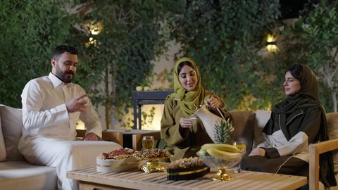 دلة القهوة العربية تراث قديم، التنزه والتسلية في شاليه سياحية في وقت العطلة ، تجسيد مفهوم حسن الضيافة والكرم العربي،اجتماع الأهل والأصدقاء في الهواء الطلق، قضاء وقت ممتع ومسلي مع مجموعة من الأصدقاء،أصدقاء عربيون خليجيون سعوديون بالزي التقليدي يشربون القهوة العربية ويتبادلون الأحاديث والقصص بإيماءات الاندماج