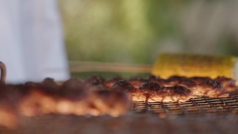 أسياخ اللحم الطازجة والذرة على الشواية، تحضير الشواء في التجمعات، فعاليات وأنشطة مسلية، التعاون والمشاركة في تحضير الطعام، تصوير مقرب لعملية الشواء تقليب اللحم على الموقد التأكد من طهيه جيدا، التنزه والتسلية في شاليه سياحي راقي وقت العطلة