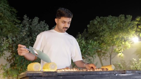 التنزه والتسلية في شاليه سياحي راقي وقت العطلة ،فعاليات وأنشطة مسلية، التعاون والمشاركة في تحضير الطعام،  تحضير الشواء في التجمعات،ولد عربي خليجي سعودي يرتدي الزي الكاجوال ويقوم بعملية الشواء تقليب اللحم على الموقد التأكد من طهيه جيدا