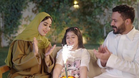 عائله عربية خليجية سعوديه ترتدي الزي التقليدي تحتفل بعيد ميلاد ابنتهم بإيماءات السعاده ،اعياد واحتفالات ومناسبات عائليه،  التنزه والتسلية في شاليه سياحي راقي وقت العطلة ، قضاء وقت ممتع ومسلي مع العائله  والأصدقاء في الهواء الطلق، فعاليات وأنشطة مسلية