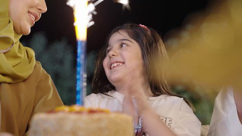 Excursion and entertainment in a luxury tourist chalet during the holiday, a Saudi Arabian Gulf family wearing traditional dress celebrating their daughter's birthday with happy gestures, holidays, celebrations and family occasions, spending a fun and entertaining time with family and friends in the open air, entertaining events and activities