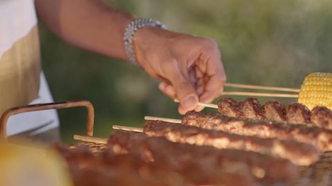 أسياخ اللحم الطازجة والذرة على الشواية، تحضير الشواء في التجمعات، فعاليات وأنشطة مسلية، التعاون والمشاركة في تحضير الطعام، تصوير مقرب لعملية الشواء تقليب اللحم على الموقد التأكد من طهيه جيدا، التنزه والتسلية في شاليه سياحي راقي وقت العطلة