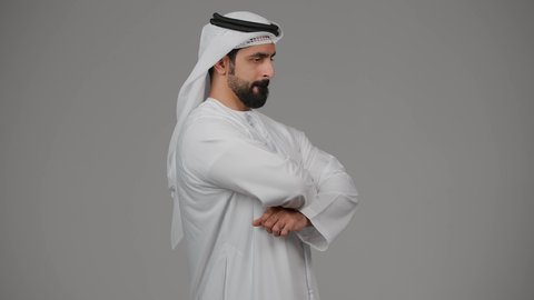 التفكير ومحاولة إيجاد حل للمشكلات, النظر بتمعن والتخطيط للمستقبل, شرود الذهن واتخاذ القرارات بتركيز, بورتريه من الجانب لشاب عربي خليجي إماراتي يرتدي الغترة والكندورة ينظر إلى شيء ما بإيماءات القلق والتفكر, خلفية رمادية