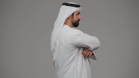 التفكير ومحاولة إيجاد حل للمشكلات, النظر بتمعن والتخطيط للمستقبل, شرود الذهن واتخاذ القرارات بتركيز, بورتريه من الجانب لشاب عربي خليجي إماراتي يرتدي الغترة والكندورة ينظر إلى شيء ما بإيماءات القلق والتفكر, خلفية رمادية