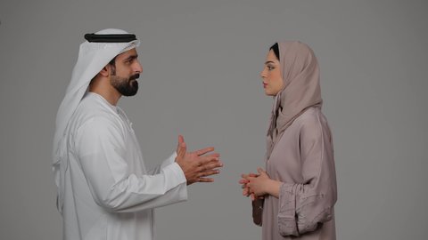 ازمة في العلاقات الاسرية، مشاكل عائلية وصراع اسري، شجار بين الزوجين، بورتريه لزوجين عربيين خليجيين اماراتيين يتجادلان مع بعضهما بإيماءات الغضب، خلفية بيضاء
