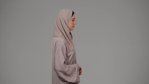 مفهوم اهميه الوقت، التأخر عن موعد محدد، بورتريه من الجانب لامرأة عربية خليجية اماراتية ترتدي العباءة والحجاب تنظر الى ساعتها الشخصيه، اهميه الالتزام بالوقت وإنجاز المهامات والاعمال بدقه، امراة سعودية تلتزم بالمواعيد، خلفية بيضاء