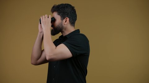 البحث عن شيء ما وتوسيع مجال الرؤية باستخدام المنظار،مفهوم الاستكشاف والمغامرة،  رؤى مستقبلية عند الشباب، تصوير لشاب عربي خليجي إماراتي يرتدي الزي الكاجوال يقفز عاليا وقوم بالنظر من خلال المنظار ثنائي العينين، خلفيه صفراء