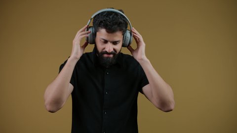 مواهب غنائية فنية،الاستماع عبر الهيدفون، إيماءات السعادة و الاندماج مع الأغنية،تصوير لشاب اماراتي يرتدي الزي الكاجوال يستمع إلى الموسيقى, تسجيل مقطع صوتي غنائي، خلفيه صفراء