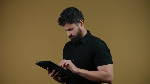 Using a tablet, using modern and advanced technology, a picture of an Arab Gulf Emirati man wearing casual clothes holding a tablet in his hand, yellow background