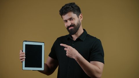 النظر إلى الكاميرا بإيماءات السعادة، استخدام التكنولوجيا الحديثة والمتطورة، عرض شاشة سوداء فارغة عبر الجهاز اللوحي، تصوير لرجل عربي خليجي اماراتي يرتدي الزي الكاجوال يمسك بيده التابلت المحمول،  خلفية صفراء