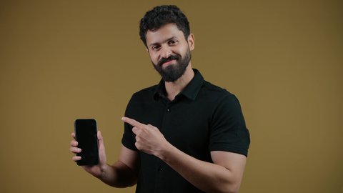 showing a blank black screen on a mobile phone, looking at the camera with happy gestures, using modern and advanced technology, a picture of an Emirati Gulf Arab man wearing casual clothes holding a mobile phone in his hand, yellow background
