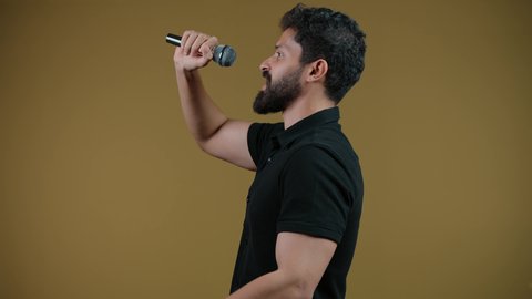 مواهب غنائية فنية، تسجيل مقطع صوتي غنائي، الاندماج مع الأغنية، تصوير لشاب عربي خليجي اماراتي يرتدي الزي الكاجوال يقوم بالغناء باستخدام الميكروفون بتعابير الحماس,  خلفيه صفراء