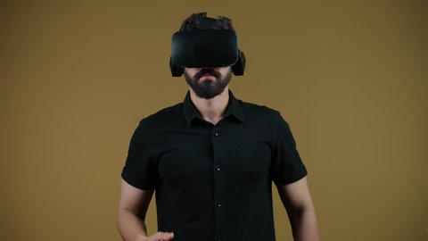 Watching movies and simulating the imaginary world, a picture of a young Emirati Gulf Arab man wearing casual clothes and 3D VR glasses, interacting and immersing himself in virtual reality games, an Emirati man raising his fist to try to grab something, yellow background