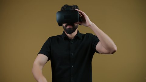Interacting and immersing in virtual reality games, watching movies and simulating the imaginary world, a picture of a young Emirati Gulf Arab man wearing casual clothes and 3D VR glasses, an Emirati man raising his fist to try to grab something, yellow background