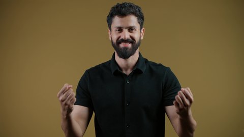 النظر إلى الكاميرا بإيماءات الفرح والسعادة لفوز الفريق المفضل، أنشطة ترفيهية ممتعة،تشجيع الأنديه والمنتخبات، رجل عربي خليجي اماراتي مبتسم يرتدي الزي الكاجوال يرفع قبضة اليد بتعابير الانتصار والحماس، خلفية صفراء