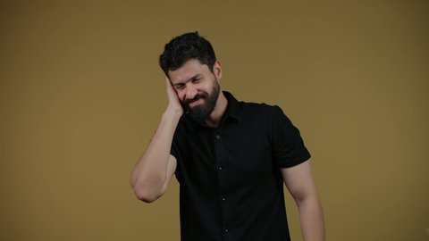 Receiving unexpected happy news, looking at the camera with gestures of wonder and amazement, feeling astonished and amazed, being surprised by a specific situation, remembering something, a picture of an Arab Gulf Emirati man wearing casual clothes with his hand on his head, yellow background