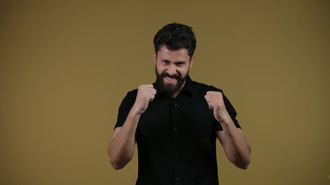 التدرب على إتقان فنون الملاكمة،نشاط رياضي بدني،  ممارسة رياضة الدفاع عن النفس، زيادة قدرة العضلات على التحمل، تصوير لشاب عربي خليجي اماراتي يرتدي الزي الكاجوال يرفع قبضات يديه بإيماءات القوة،  خلفية صفراء