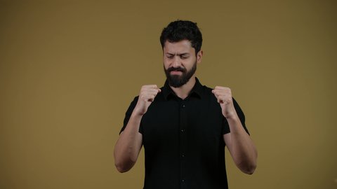 نشاط رياضي بدني، ممارسة رياضة الدفاع عن النفس، التدرب على إتقان فنون الملاكمة، زيادة قدرة العضلات على التحمل، تصوير لشاب عربي خليجي اماراتي يرتدي الزي الكاجوال يرفع قبضات يديه بإيماءات القوة،  خلفية صفراء