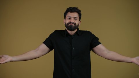 Surprise and inquiry about something, mockery of an ambiguous topic, a picture of a young Arab Gulf Emirati man wearing casual clothes, looking at the camera and raising his hands up with gestures of ignorance, hesitation and lack of confidence, feeling confused and mysterious, yellow background