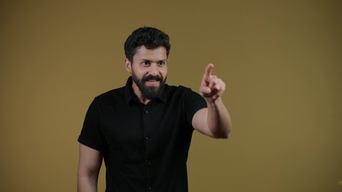 مفهوم الأناقة والاهتمام بالمظهر الخارجي، الاشارة بإصبع السبابة إلى شيء ما، تصوير لشاب عربي خليجي إماراتي يرتدي الزي الكاجوال يقف باستقامة ويحدد موقع معين ، خلفية صفراء