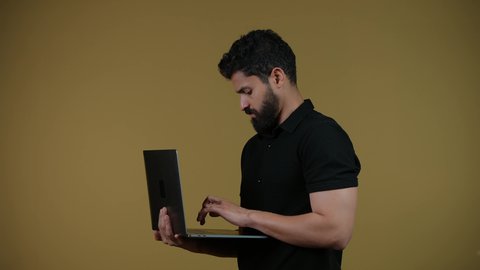 استعمال التكنولوجيا الحديثة والمتطورة، اجراء اجتماع عمل اونلاين، استخدام اللابتوب في إنجاز مهام العمل عن بعد، تصوير لرجل عربي خليجي اماراتي يرتدي الزى الكاجوال يستخدم جهاز الحاسوب بإيماءات التركيز،  خلفية صفراء