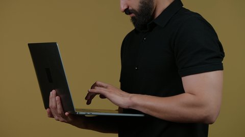 اجراء اجتماع عمل اونلاين، استعمال التكنولوجيا الحديثة والمتطورة، استخدام اللابتوب في إنجاز مهام العمل عن بعد، تصوير لرجل عربي خليجي اماراتي يرتدي الزى الكاجوال يستخدم جهاز الحاسوب بإيماءات التركيز،  خلفية صفراء