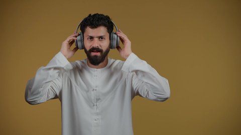 إيماءات السعادة و الاندماج مع الأغنية،  مواهب غنائية فنية، الاستماع عبر الهيدفون،  تصوير لشاب اماراتي يرتدي الكندورة يستمع إلى الموسيقى, تسجيل مقطع صوتي غنائي، خلفيه صفراء