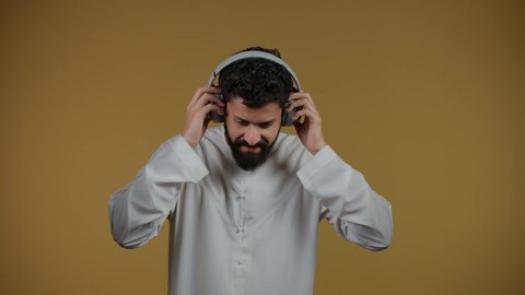 مواهب غنائية فنية،الاستماع عبر الهيدفون، إيماءات السعادة و الاندماج مع الأغنية،تصوير لشاب اماراتي يرتدي الكندورة يستمع إلى الموسيقى, تسجيل مقطع صوتي غنائي، خلفيه صفراء