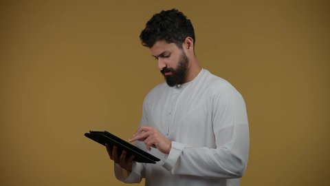 Using modern and advanced technology, gestures of integration and interaction, a picture of an Emirati Gulf Arab man wearing a kandura holding a tablet in his hand, integrating modern technologies into daily life, yellow background