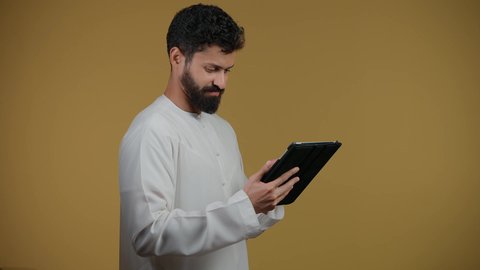 Integrating modern technologies into daily life, gestures of integration and interaction, the use of modern and advanced technology, a picture of an Arab Gulf Emirati man wearing a kandura holding a tablet, yellow background