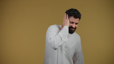 الشعور بالدهشة والذهول, تلقي اخبار سعيدة غير متوقعة، النظر إلى الكاميرا بايماءات الصدمة والتعجب والانبهار, التفاجؤ من موقف محدد، تذكر شيء ما، تصوير لرجل عربي خليجي اماراتي يرتدي الكندورة يضع يديه على رأسه، خلفية صفراء