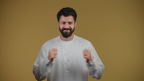 Increasing muscle endurance, practicing self-defense, training to master the art of boxing, physical activity, a picture of a young Arab Gulf Emirati man wearing a kandura raising his fists with gestures of strength, yellow background