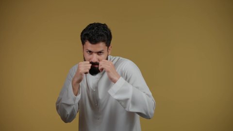 ممارسة رياضة الدفاع عن النفس، التدرب على إتقان فنون الملاكمة،  نشاط رياضي بدني،زيادة قدرة العضلات على التحمل، تصوير لشاب عربي خليجي اماراتي يرتدي الكندورة يرفع قبضات يديه بإيماءات القوة، خلفية صفراء