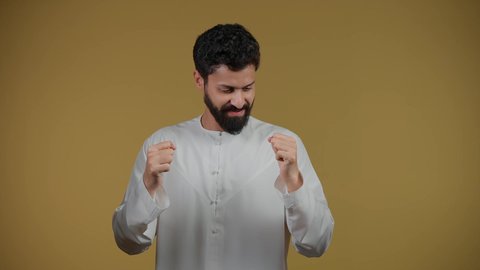 نشاط رياضي بدني، ممارسة رياضة الدفاع عن النفس، التدرب على إتقان فنون الملاكمة، زيادة قدرة العضلات على التحمل، تصوير لشاب عربي خليجي اماراتي يرتدي الكندورة يرفع قبضات يديه بإيماءات القوة، خلفية صفراء