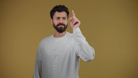 Pointing the index finger at something, the concept of elegance and interest in one's outward appearance, a picture of a young Emirati Gulf Arab man wearing a kandura, standing straight and pointing to a specific location, yellow background