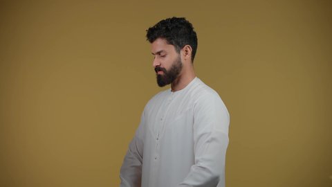 استخدام العدسات الطبية لحماية العين من أشعة الشمس، الأناقة والوسامة والاهتمام بالمظهر الخارجي، تصوير لرجل عربي خليجي اماراتي يرتدي الكندورة يقف بإيماءات الثقة بالنفس ويضع نظارة شمسية سوداء، خلفية صفراء