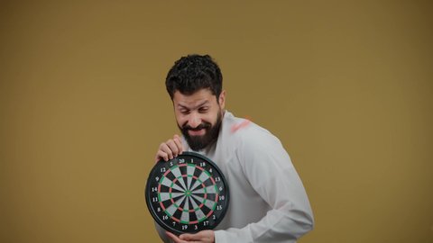Entertainment and sports skills, expressions of pleasure and happiness, the concept of focus and goal setting, a picture of a smiling Emirati Gulf Arab man wearing a kandura holding a magnetic darts game, yellow background