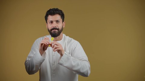 مفهوم التركيز وتحديد الأهداف, تسليه وترفيه و مهارات رياضية، تعابير السرور والسعادة, تصوير لرجل عربي خليجي اماراتي مبتسم يرتدي الكندورة يحمل لعبة السهام المغناطيسية، خلفية صفراء