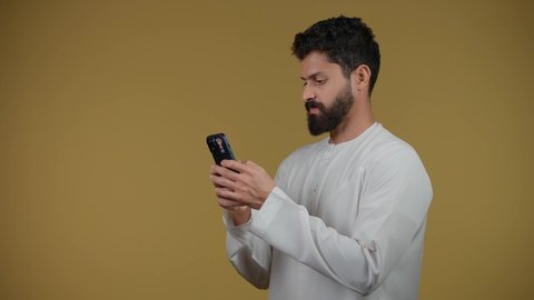 دمج التقنيات الحديثة والتكنولوجيا بالحياة العملية, التواصل مع الأهل والأصدقاء, متابعة آخر الأخبار والمستجدات حول العالم, تصوير لشاب عربي خليجي اماراتي يرتدي الكندورة يقوم باستخدام الهاتف المحمول، خلفية صفراء