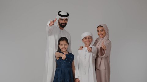 إيماءات الامتياز والجودة، مفهوم القبول والموافقه، أجواء أسرية مليئة بالمودة، المشي و التنزه مع الأطفال، بورتريه لام عربيه خليجيه اماراتية ترتدي العباءه الملونه تقوم بقضاء وقت ممتع برفقه اولادها و زوجها ، خلفية رمادية